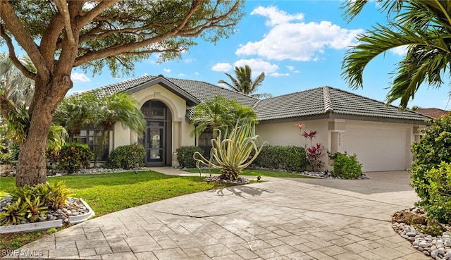 view of front facade with concrete driveway, stucco siding, a tile roof, an attached garage, and a front yard