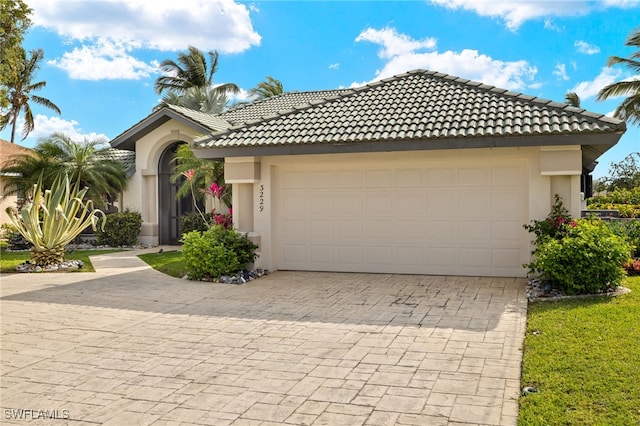 view of front facade with a garage, decorative driveway, a tile roof, and stucco siding