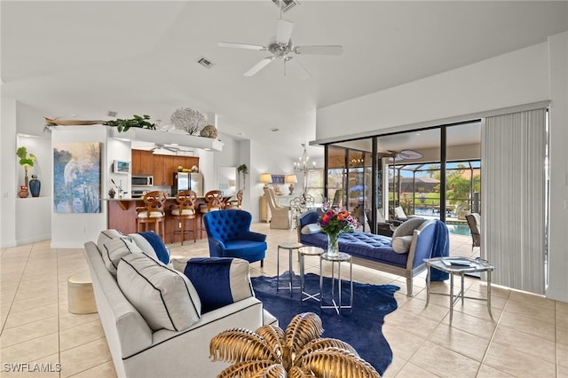 living room featuring ceiling fan with notable chandelier, visible vents, and light tile patterned floors