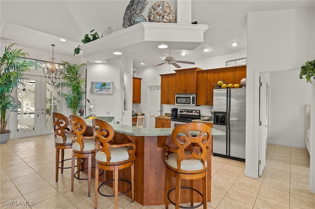 kitchen featuring appliances with stainless steel finishes, brown cabinetry, a kitchen breakfast bar, and light tile patterned floors