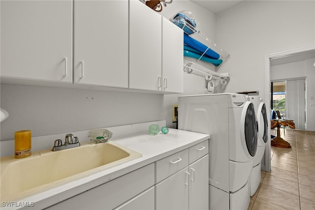 laundry room featuring cabinet space, light tile patterned floors, washer and clothes dryer, and a sink