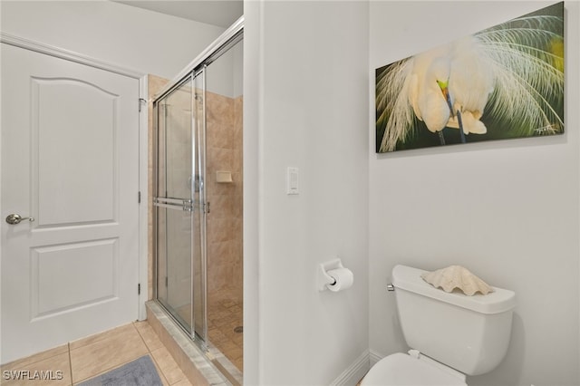 bathroom featuring tile patterned flooring, a shower stall, toilet, and baseboards