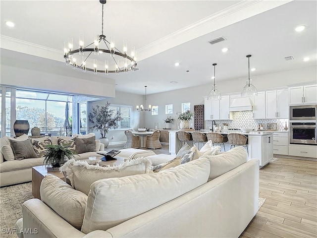 7041 Del Webb Oak Creek Blvd, North Fort Myers, FL 33917 - living room with light wood finished floors, visible vents, ornamental molding, and a notable chandelier