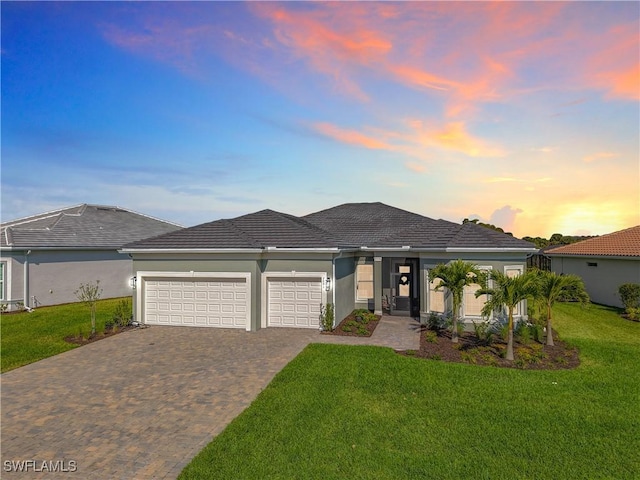 view of front of property featuring an attached garage, stucco siding, decorative driveway, and a front yard