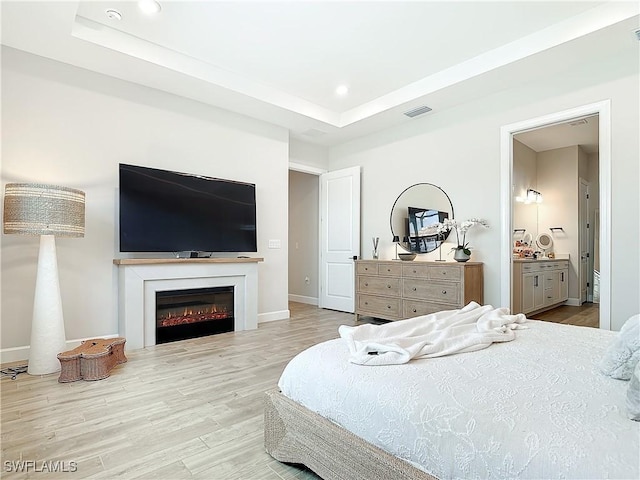 7041 Del Webb Oak Creek Blvd, North Fort Myers, FL 33917 - bedroom featuring a warm lit fireplace, visible vents, a raised ceiling, wood finished floors, and recessed lighting