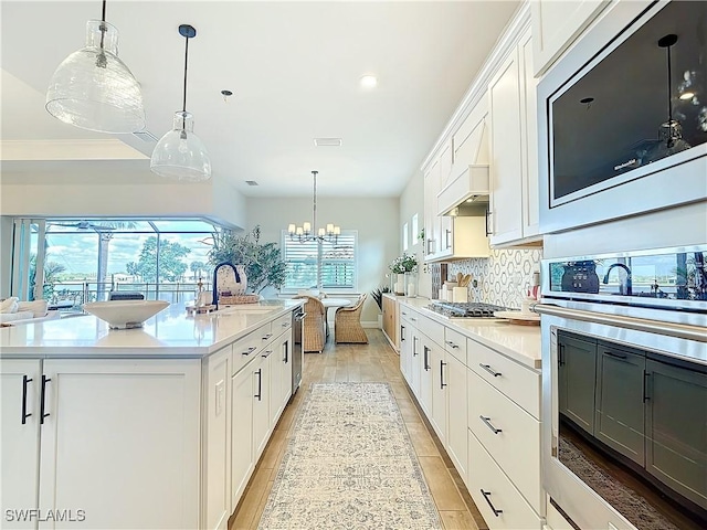 7041 Del Webb Oak Creek Blvd, North Fort Myers, FL 33917 - kitchen featuring tasteful backsplash, light countertops, white cabinetry, a sink, and a chandelier