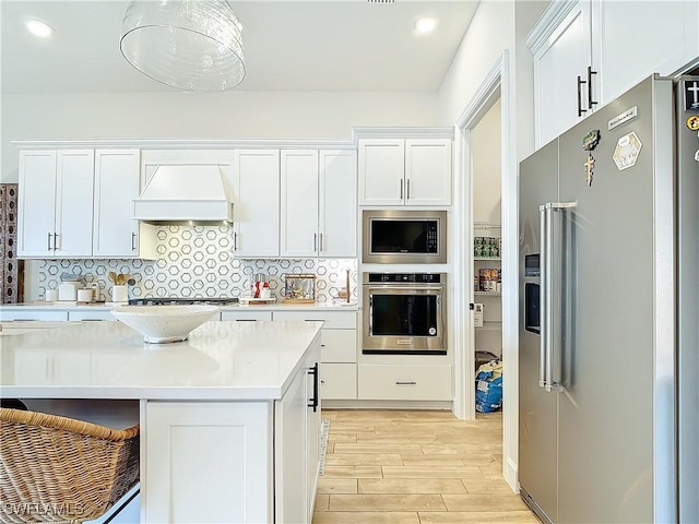 7041 Del Webb Oak Creek Blvd, North Fort Myers, FL 33917 - kitchen featuring white cabinets, premium range hood, stainless steel appliances, and decorative backsplash