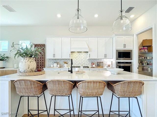 7041 Del Webb Oak Creek Blvd, North Fort Myers, FL 33917 - kitchen featuring appliances with stainless steel finishes, backsplash, custom exhaust hood, and visible vents