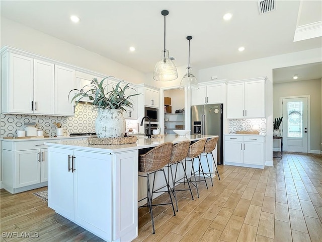 7041 Del Webb Oak Creek Blvd, North Fort Myers, FL 33917 - kitchen with light wood-style flooring, stainless steel appliances, visible vents, white cabinets, and light countertops