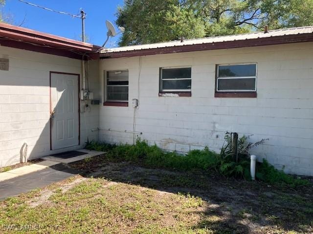 doorway to property featuring concrete block siding and metal roof