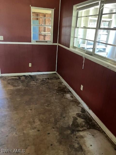 spare room with baseboards and concrete flooring