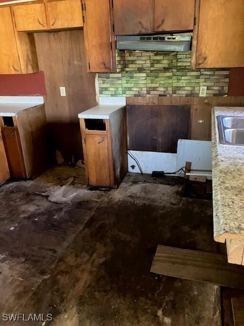 kitchen featuring under cabinet range hood, brown cabinetry, and light countertops