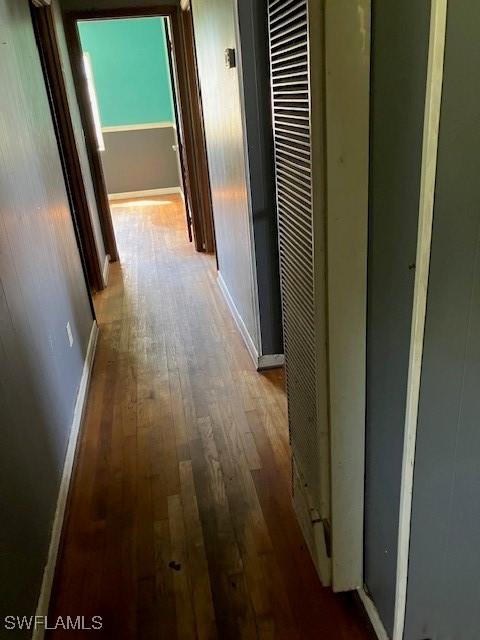 corridor with baseboards and hardwood / wood-style floors