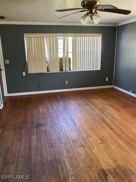 empty room with crown molding, a ceiling fan, and wood finished floors