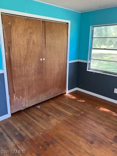 unfurnished bedroom with a closet, baseboards, and wood finished floors