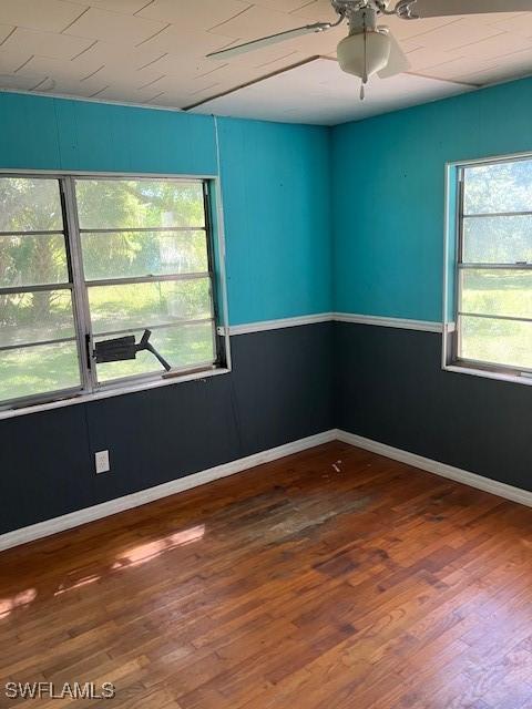 empty room featuring a ceiling fan, wood finished floors, and baseboards