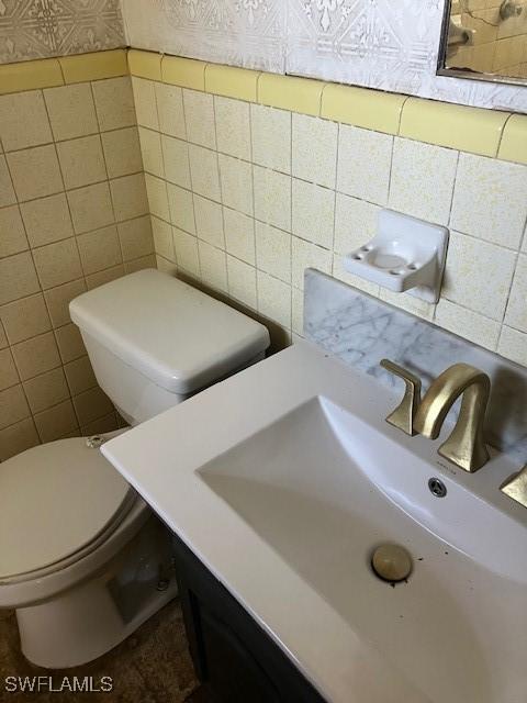 bathroom featuring tile walls, toilet, and a sink