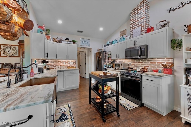 kitchen with tasteful backsplash, lofted ceiling, appliances with stainless steel finishes, dark wood-style flooring, and a sink