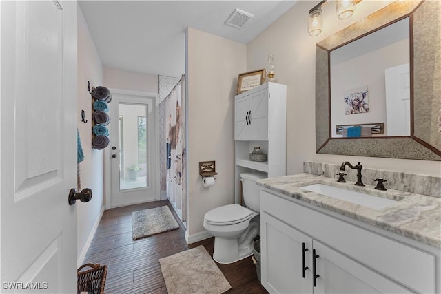 bathroom featuring visible vents, toilet, vanity, wood finished floors, and baseboards