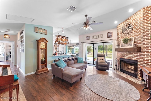 living room with wood finished floors, a ceiling fan, visible vents, baseboards, and a brick fireplace