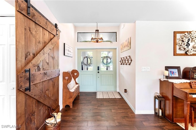 foyer featuring a barn door, baseboards, dark wood-style flooring, and french doors