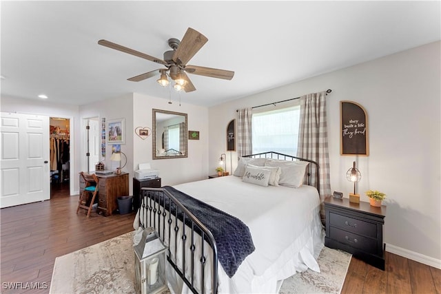 bedroom with recessed lighting, wood finished floors, a ceiling fan, baseboards, and a spacious closet