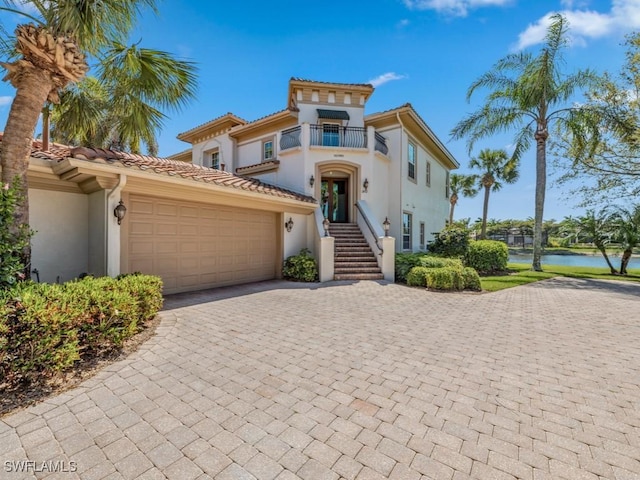 mediterranean / spanish-style house with stucco siding, a balcony, a garage, and a tile roof