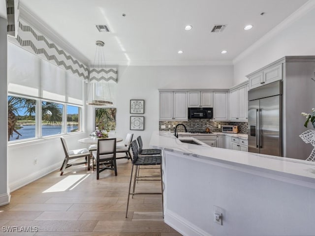 kitchen with stainless steel built in refrigerator, visible vents, backsplash, and black microwave