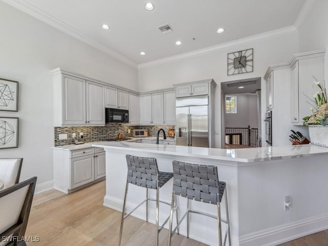 kitchen featuring visible vents, light wood finished floors, stainless steel appliances, light countertops, and crown molding