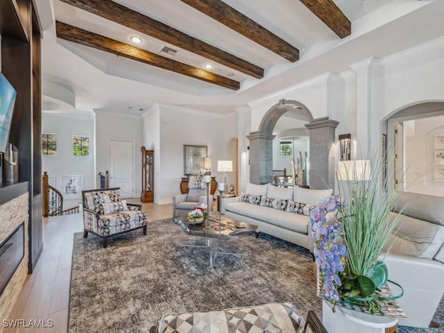 living room featuring visible vents, crown molding, beamed ceiling, wood finished floors, and arched walkways