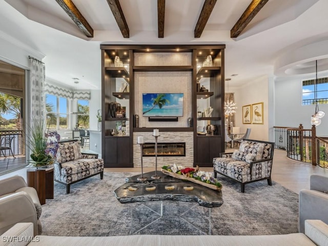 living area featuring wood finished floors, a large fireplace, beam ceiling, and a chandelier