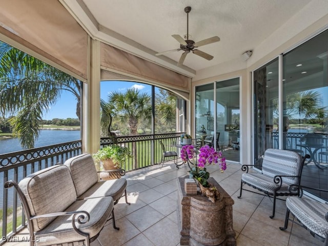 sunroom featuring ceiling fan and a water view