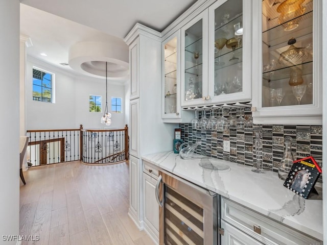 bar with pendant lighting, wine cooler, light wood finished floors, decorative backsplash, and a dry bar