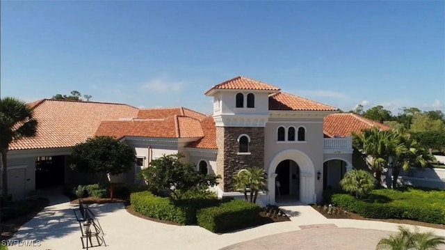 mediterranean / spanish-style home featuring stone siding, stucco siding, and a tiled roof