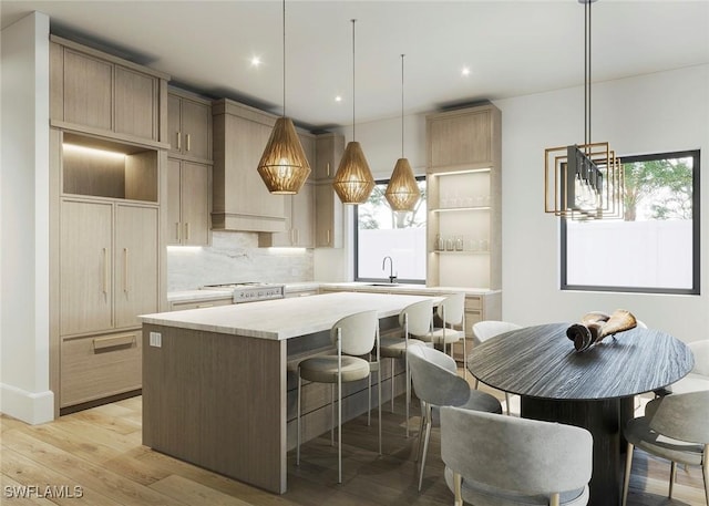 kitchen with custom exhaust hood, tasteful backsplash, light countertops, light wood-style flooring, and a kitchen island