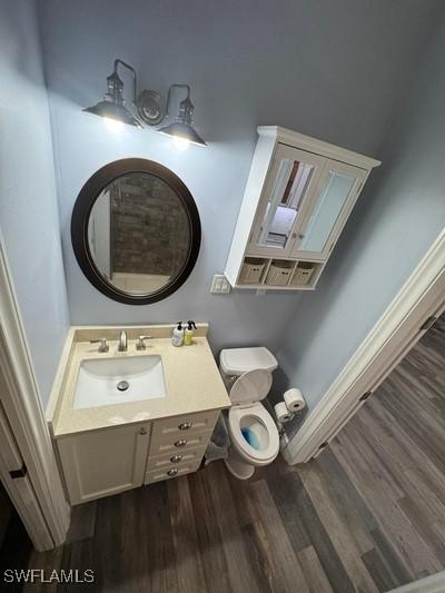 bathroom with toilet, wood finished floors, and vanity