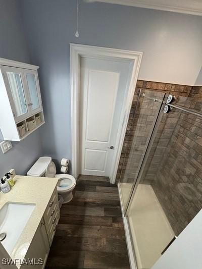 bathroom with toilet, a stall shower, wood finished floors, and vanity