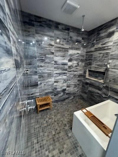 full bath featuring tile patterned flooring, a tile shower, and tile walls