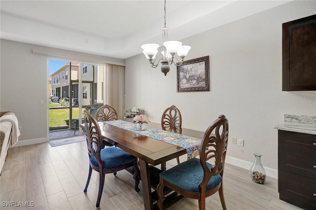 dining area featuring a notable chandelier, baseboards, and light wood-style floors