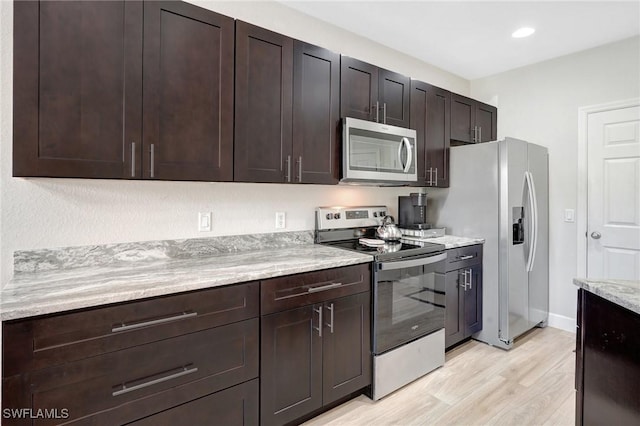 kitchen with light wood-style flooring, light stone counters, recessed lighting, appliances with stainless steel finishes, and dark brown cabinets