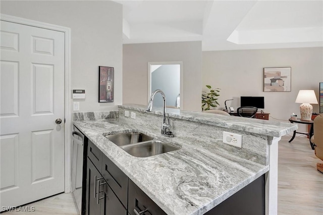 kitchen featuring light stone counters, a peninsula, and a sink