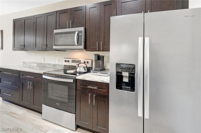 kitchen with light stone counters, dark brown cabinets, and appliances with stainless steel finishes