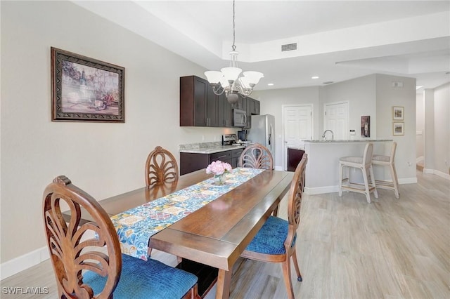 dining area featuring visible vents, baseboards, light wood-style floors, and a chandelier