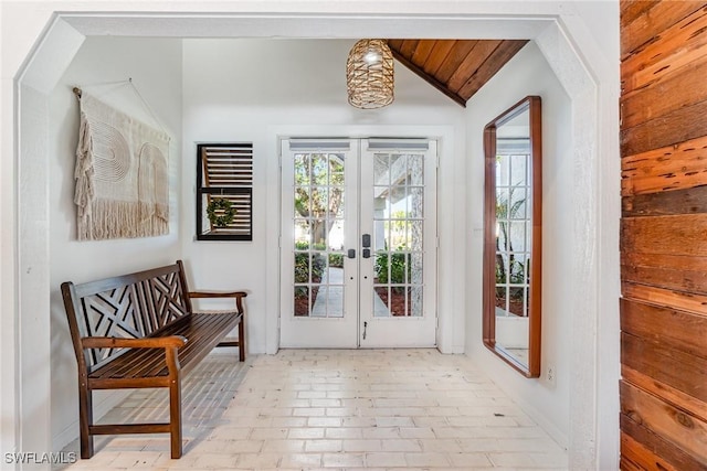 entryway with brick patterned floors, vaulted ceiling, french doors, and baseboards