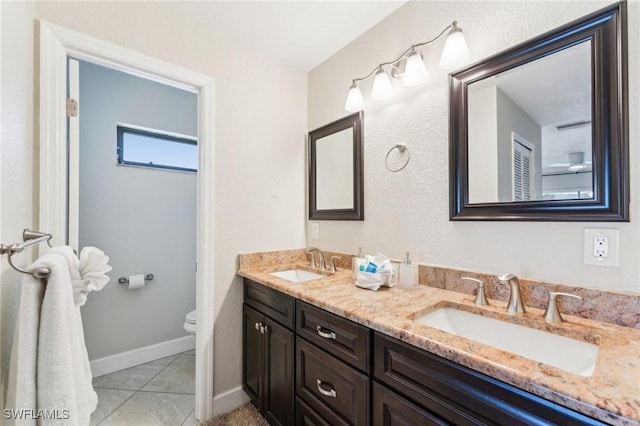 bathroom featuring a sink, toilet, double vanity, and tile patterned flooring