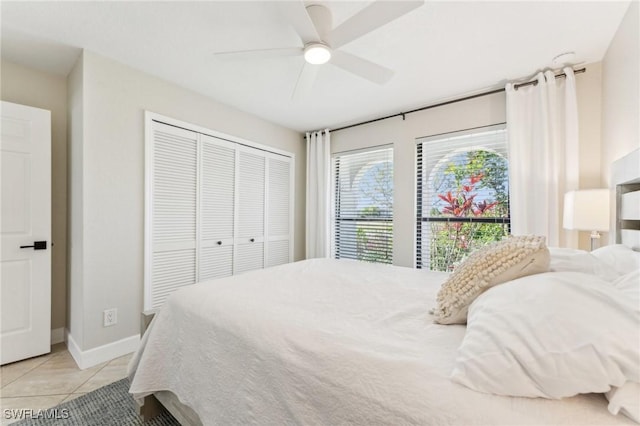 bedroom featuring ceiling fan, a closet, baseboards, and light tile patterned flooring