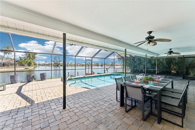 outdoor pool with glass enclosure, a patio area, and a water view