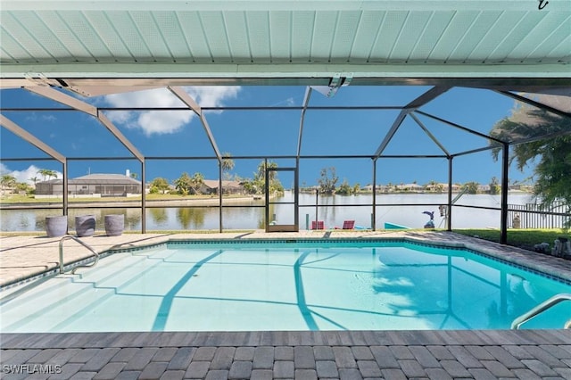 outdoor pool with glass enclosure, a patio area, and a water view