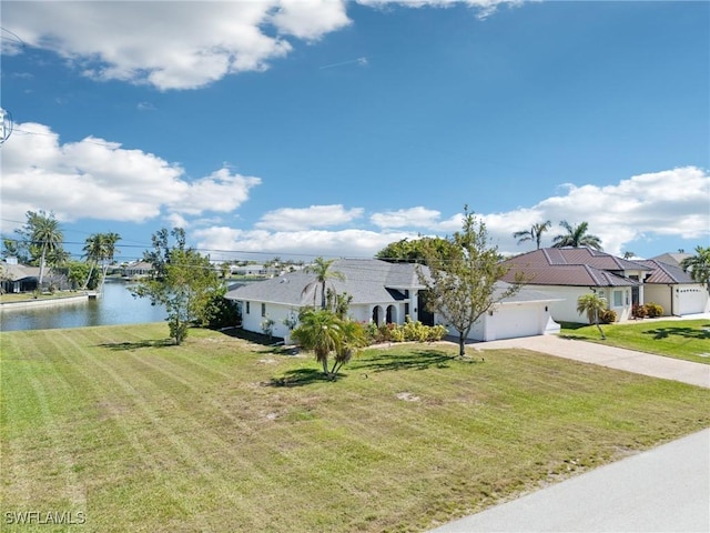 ranch-style home featuring driveway, an attached garage, a front lawn, and a water view