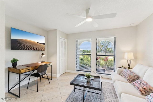 living area featuring light tile patterned floors, baseboards, and ceiling fan